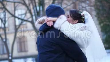 冬季婚礼。 新婚夫妇穿着婚纱。 新婚之吻，拥抱。 情人的浪漫之吻。 他们很高兴
